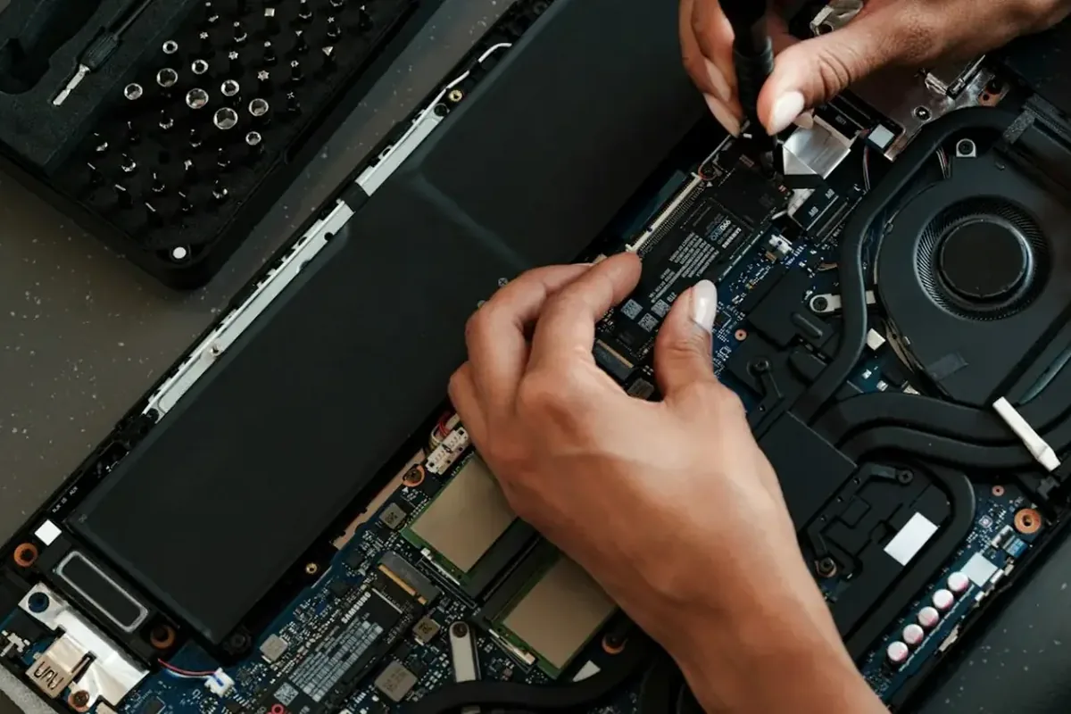 Dłonie montujące dysk SSD Samsung we wnętrzu laptopa