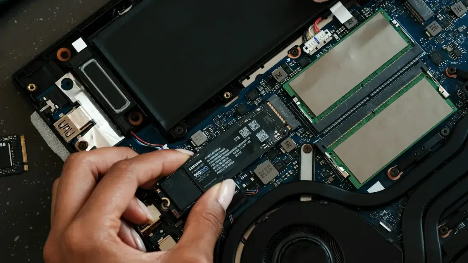 Dłoń montująca dysk SSD Samsung do płyty głównej laptopa przy śrubokręcie