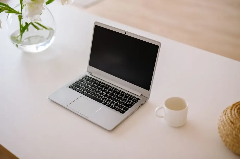 Srebrny laptop z pustym ekranem na białym biurku