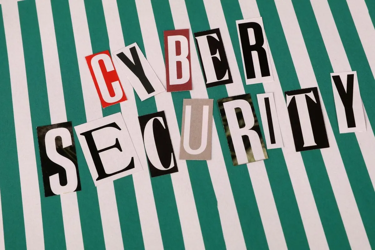 napis CYBER SECURITY ułożony z wyciętych liter na paskowanym tle — Pracownik kliknął podejrzany link — pierwsze kroki po phishingu