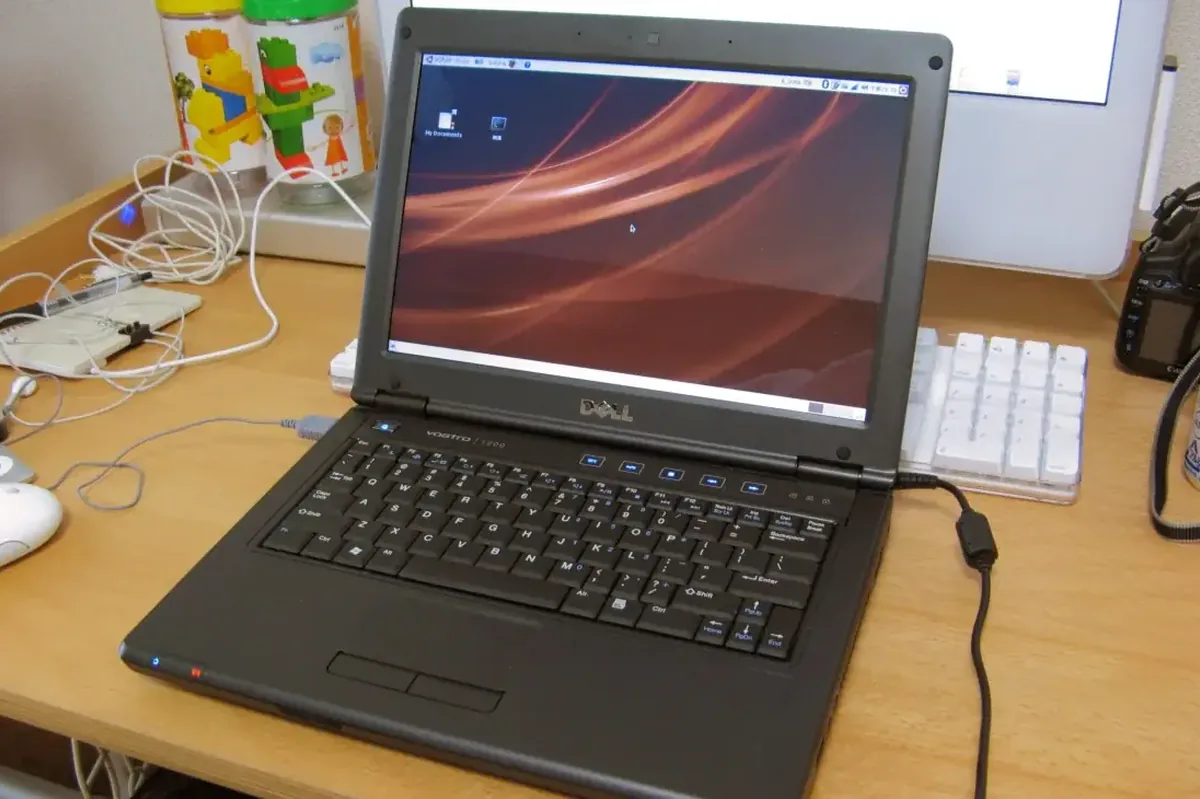 Laptop Dell z systemem Windows na biurku obok zabawek dziecięcych i myszki