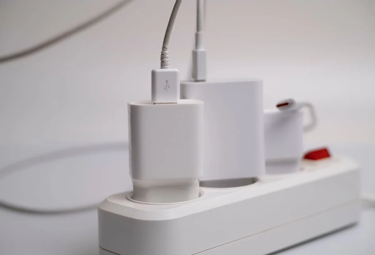 Biała listwa zasilająca z podłączonymi ładowarkami i kablami USB