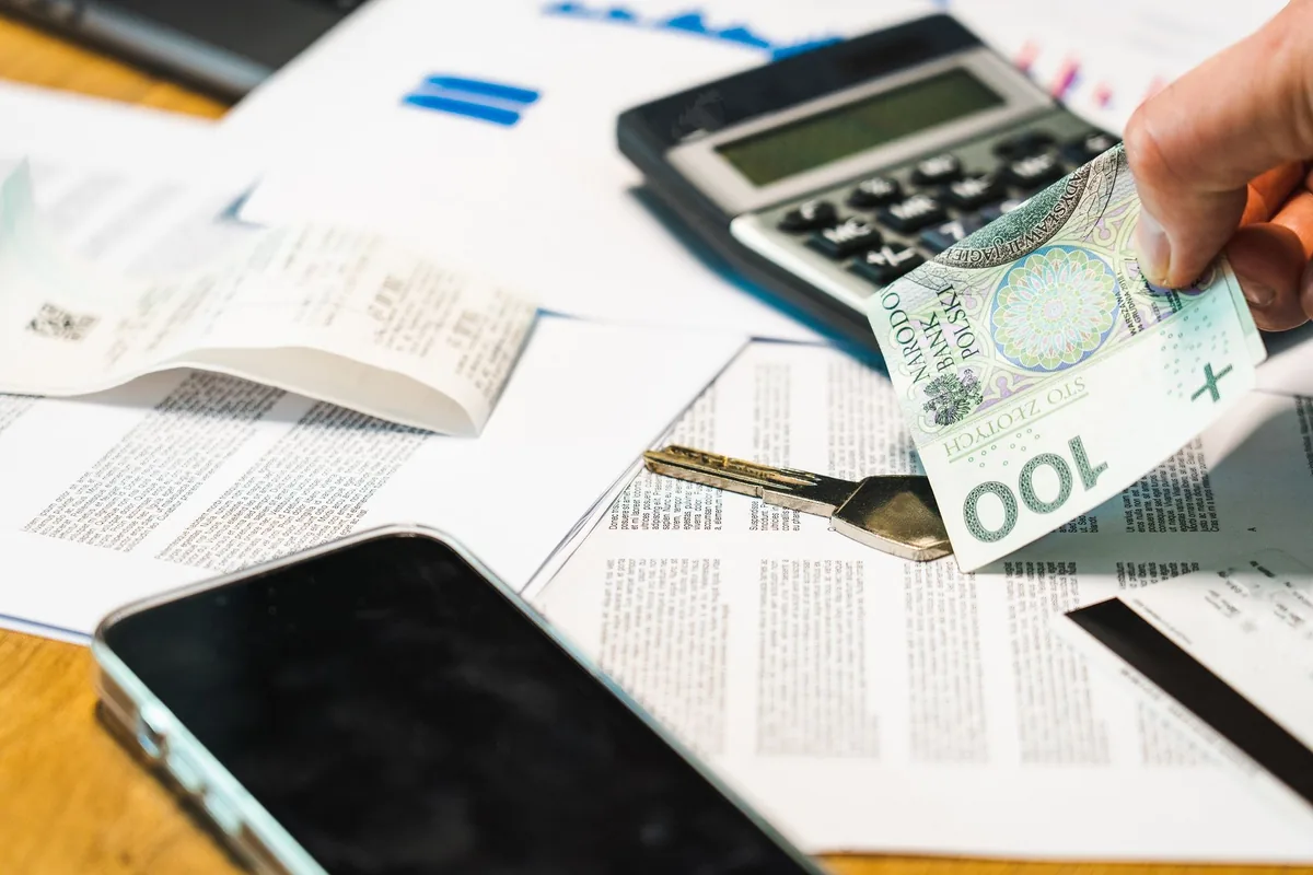 Close-up of financial documents, calculator, and Polish Zloty currency on a desk.