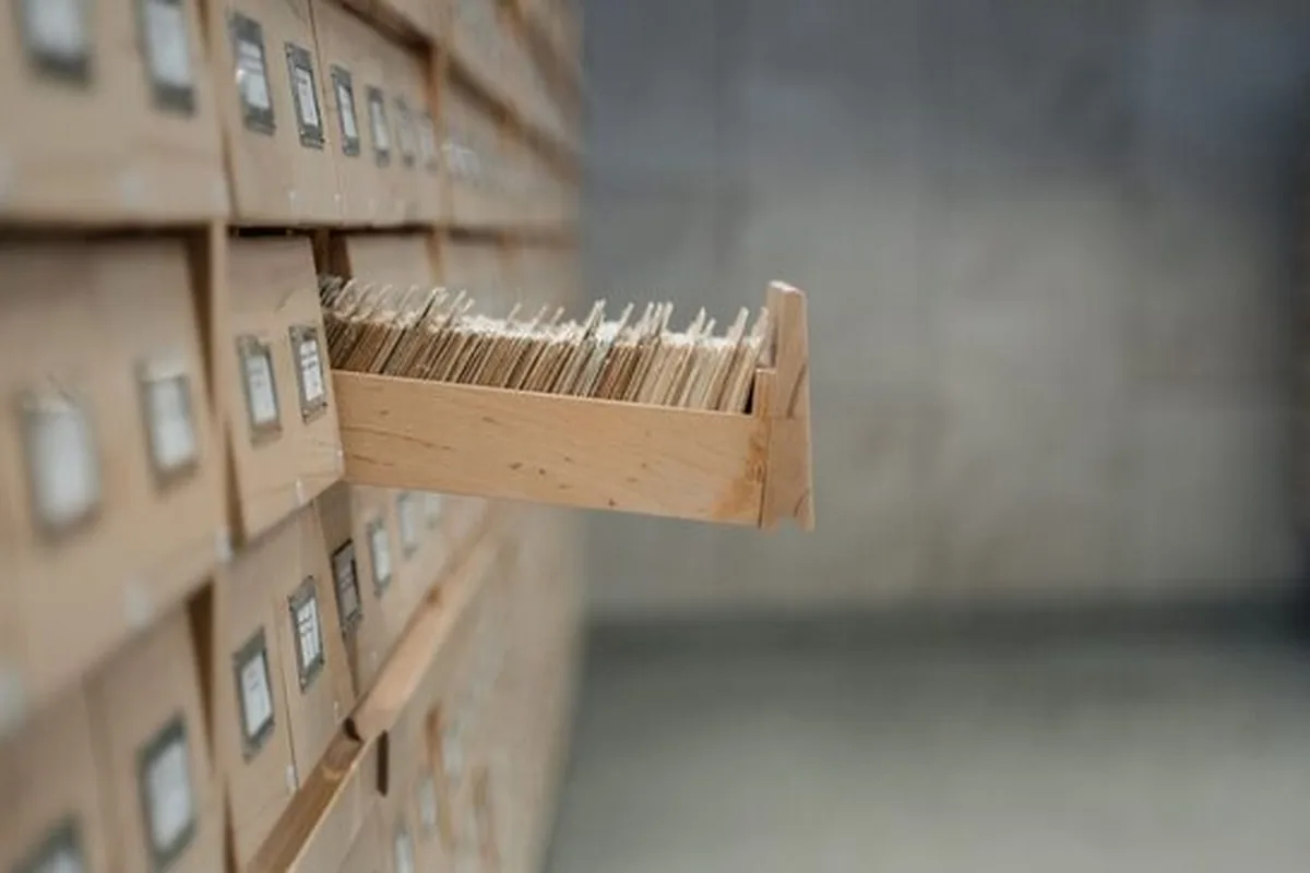 Drewniana kartoteka biblioteczna z wysuniętą szufladą pełną kart katalogowych